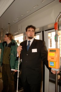 niewidomy mężczyzna z białą lską stoi w tramwaju